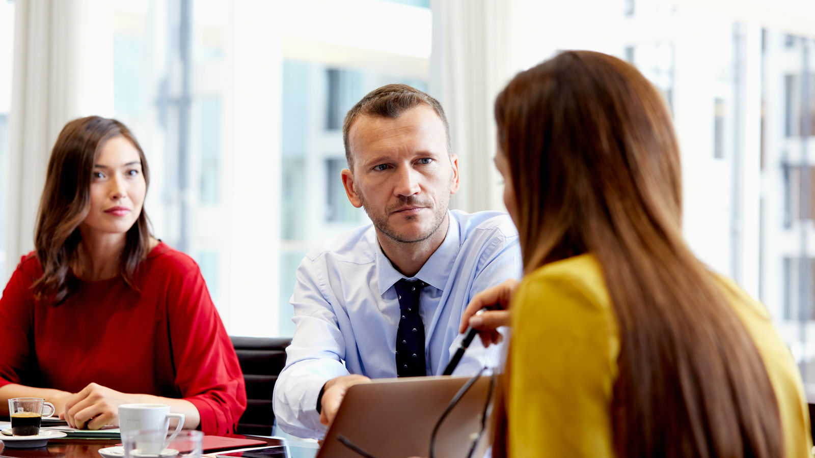 Two women and a man sitting around a table discussing in an office