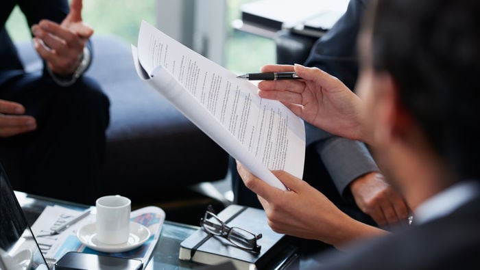 Person holding a pile of papers in the middle of a group